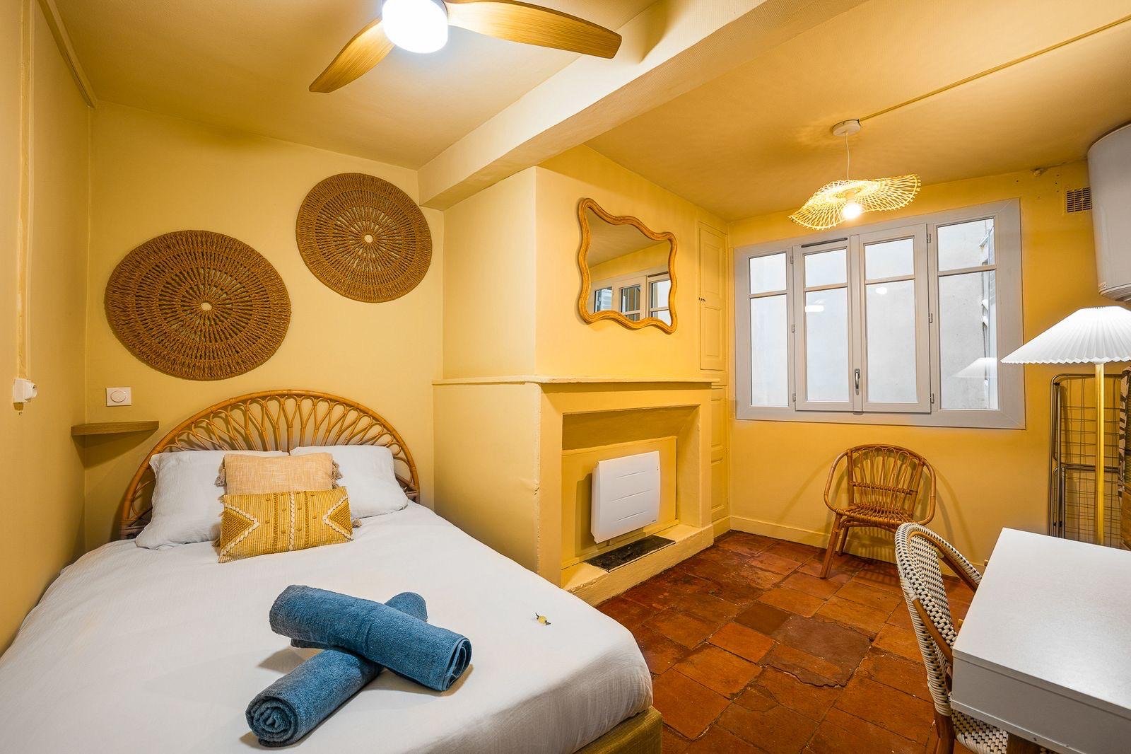 Chambre jaune lumineuse avec cheminée, miroir doré et décoration en rotin