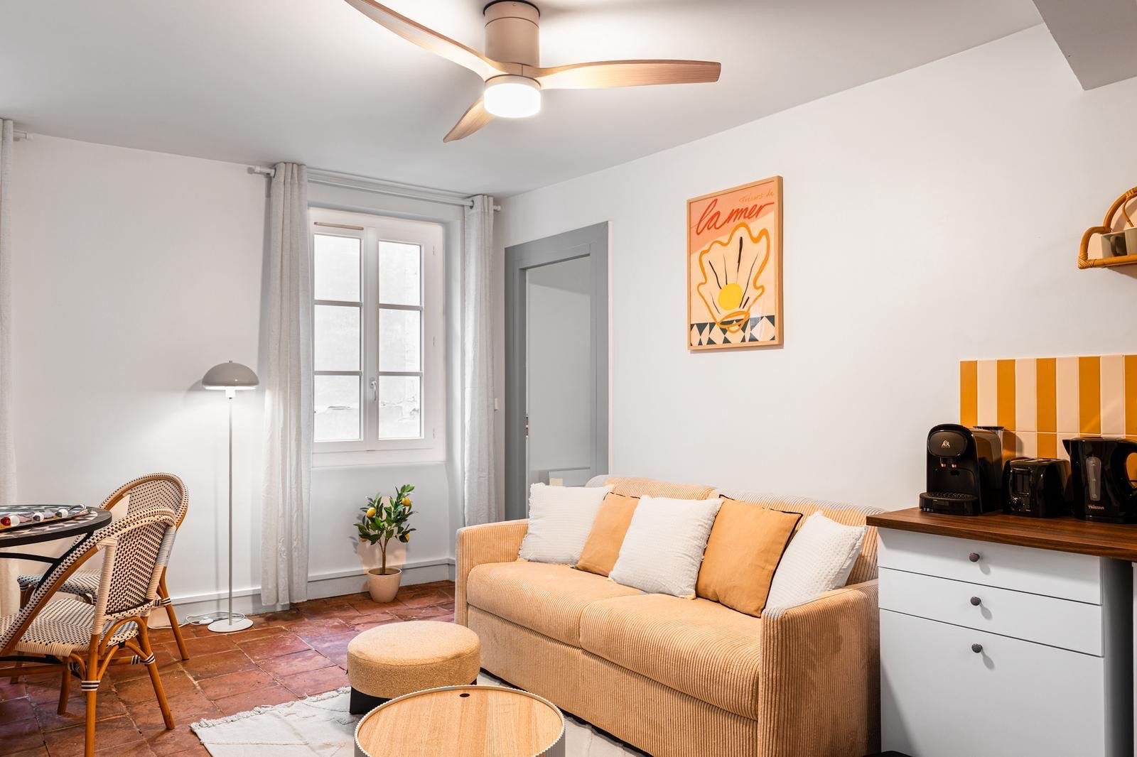 Salon convivial avec canapé beige, ventilateur de plafond et coin repas