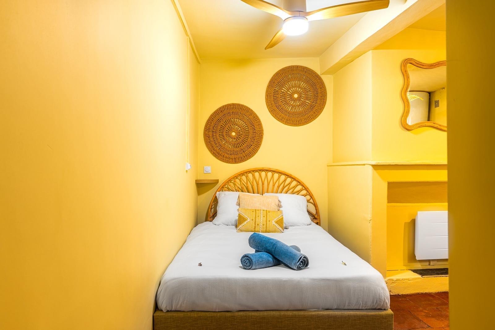 Chambre jaune avec tête de lit en rotin et paniers décoratifs